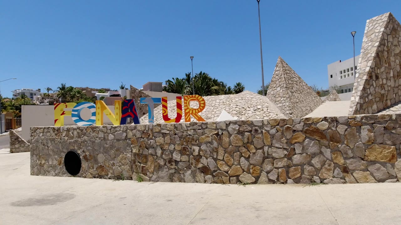 Colorful ZONATUR sign on a stone wall under a blue sky.