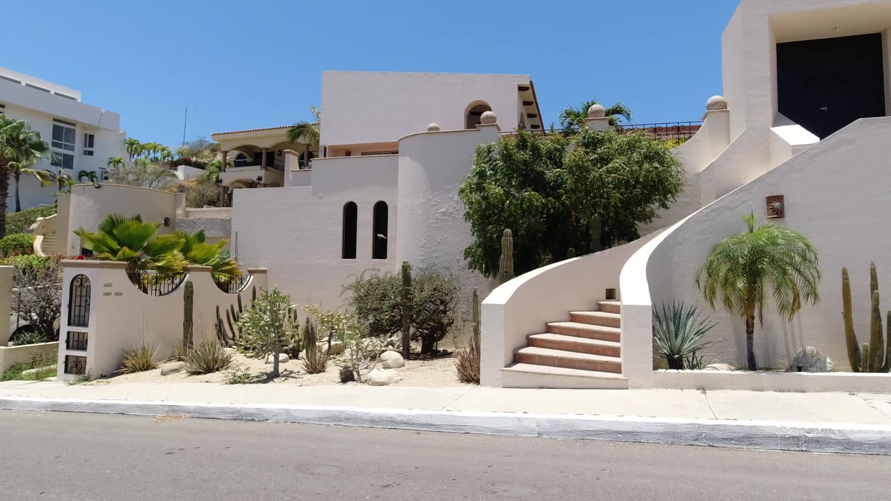 Curving exterior stairs and white walls along a sunny road