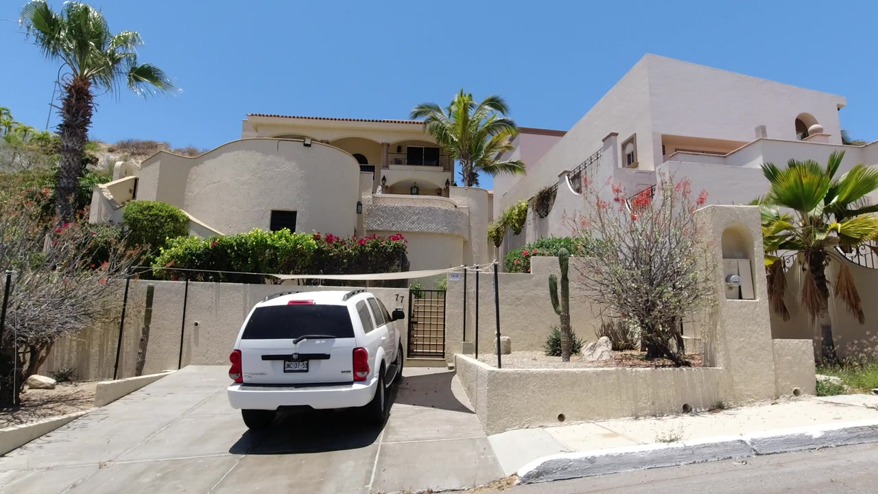 Cream hillside house with white Wrangler in a driveway