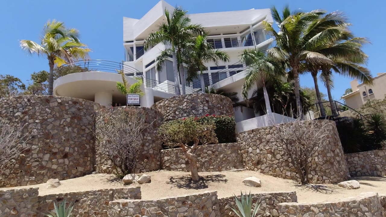 White modern building above stone walls and palm trees