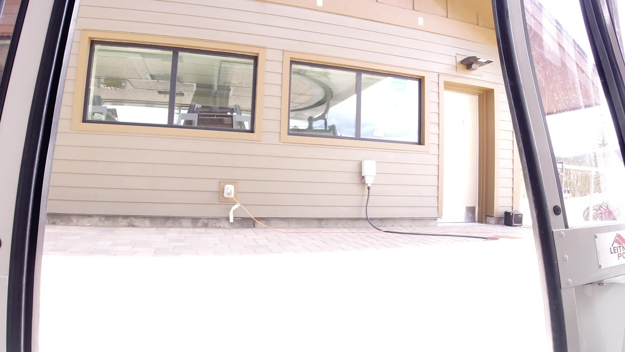 At the start of the Winter Park, Colorado clip, a dark open vehicle door frame borders a beige exterior wall with high windows and no visible people.