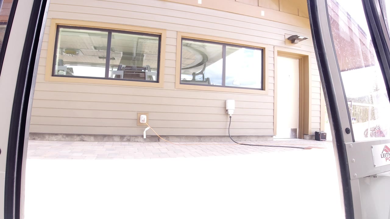 One second in, the Winter Park view holds on beige horizontal siding, two upper windows, a recessed doorway, and dark vehicle door rails with no visible people.