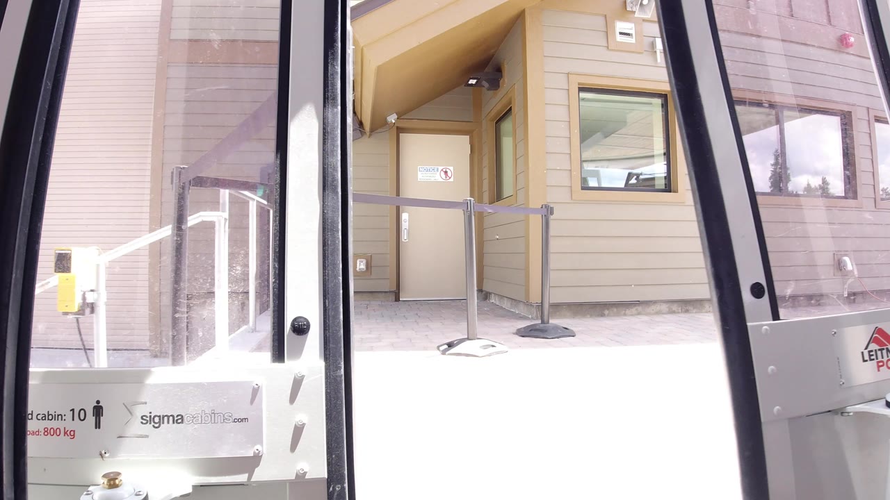 Glass vehicle door beside a beige building entrance and railings.