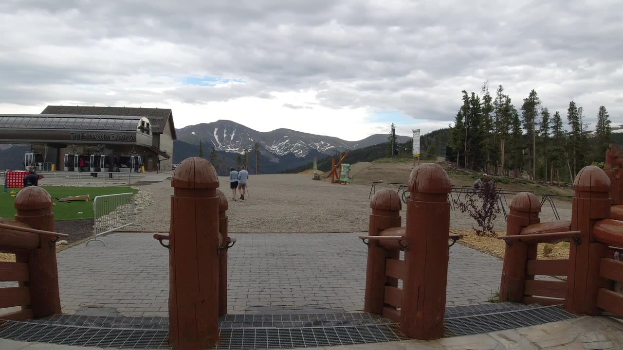 Resort building and mountain backdrop with timber posts and small turf area.