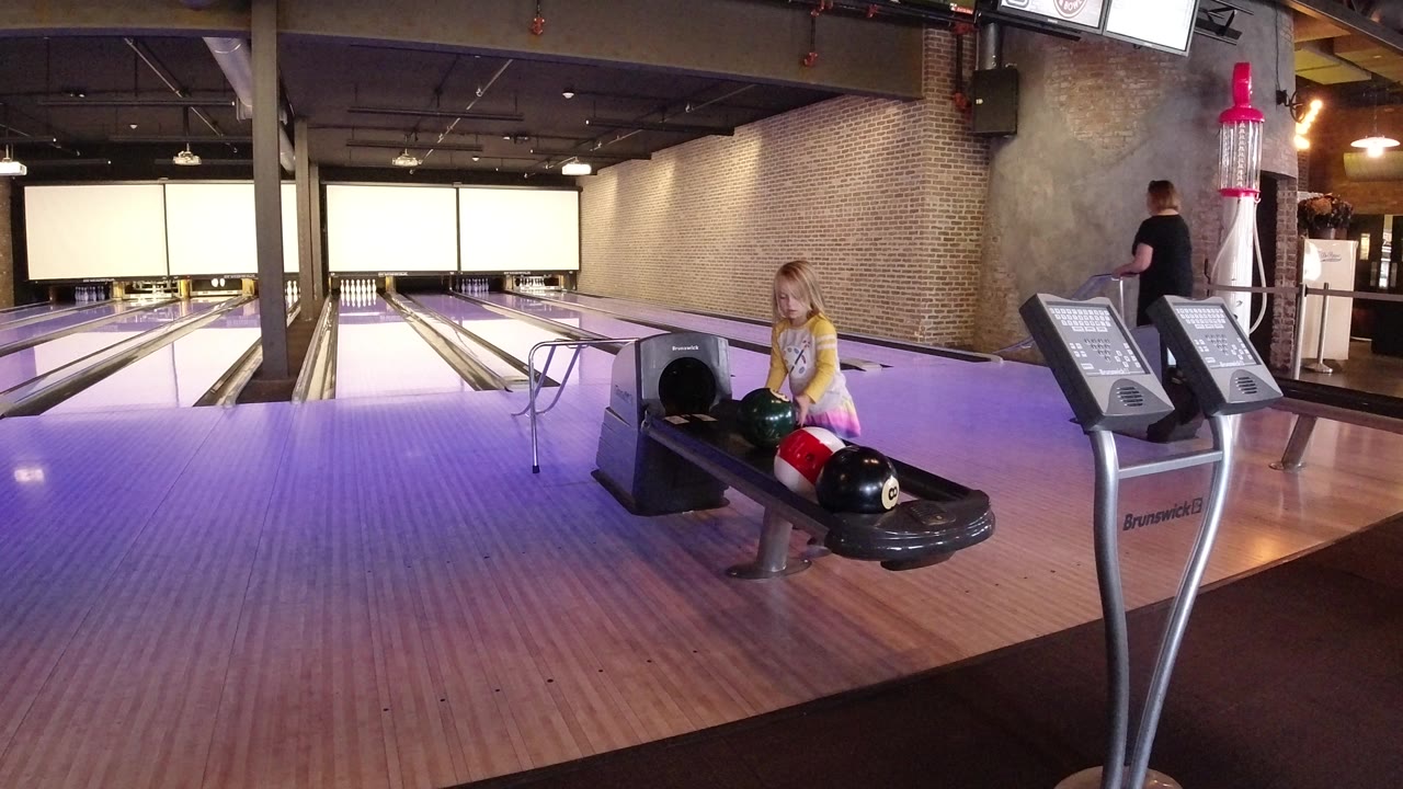 One second into the Winter Park, Colorado footage, the child remains beside the ball return as a man stands near the scoring consoles and the bowling lanes run back under indoor lights.