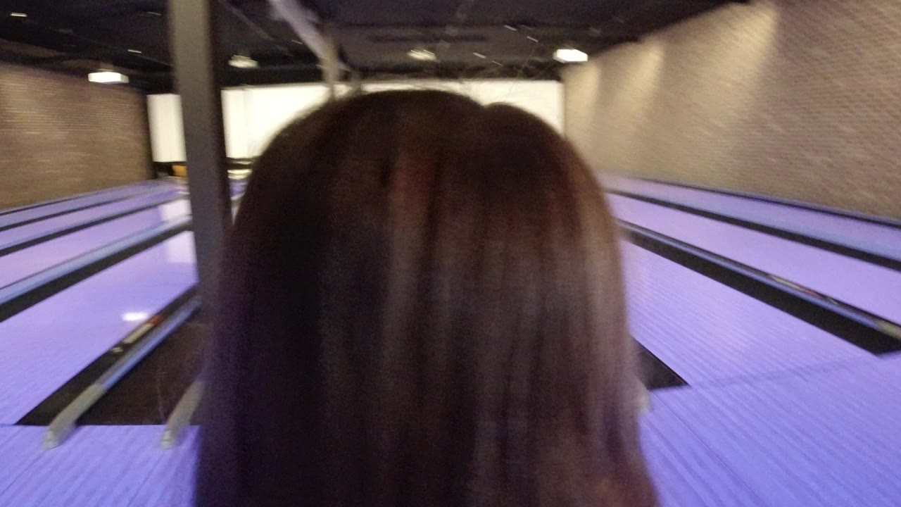 The back of the child's head fills the foreground while the bowling lanes stretch toward the pins under purple lighting in Winter Park, Colorado.