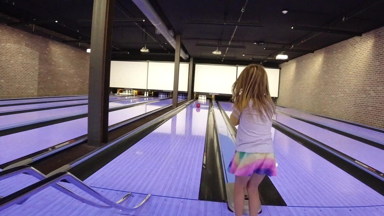 Young girl facing bowling lanes after a roll.
