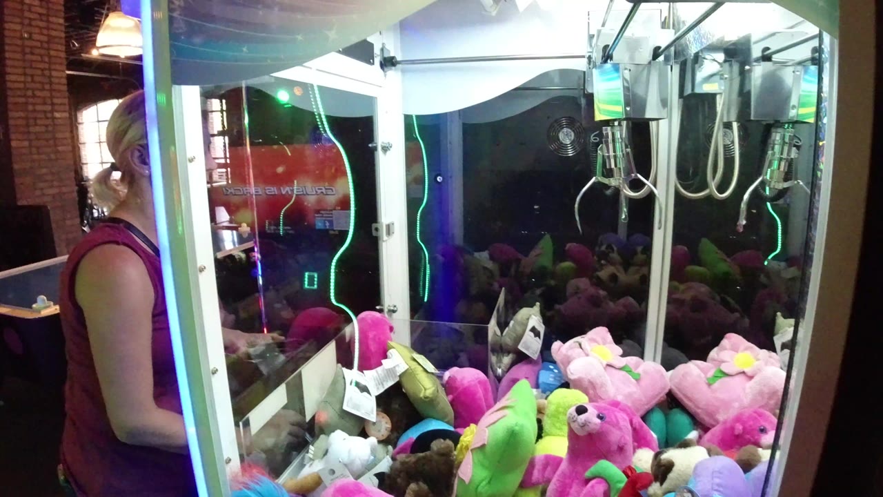 Woman beside a claw machine filled with plush toys.