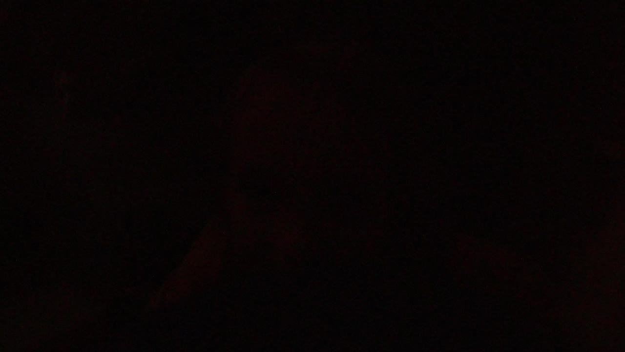 Nearly black room with faint reddish shapes and a dim window area.