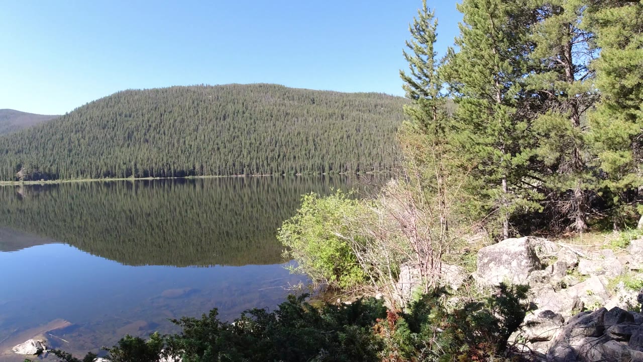 Clear mountain lake with shallow foreground water and trees