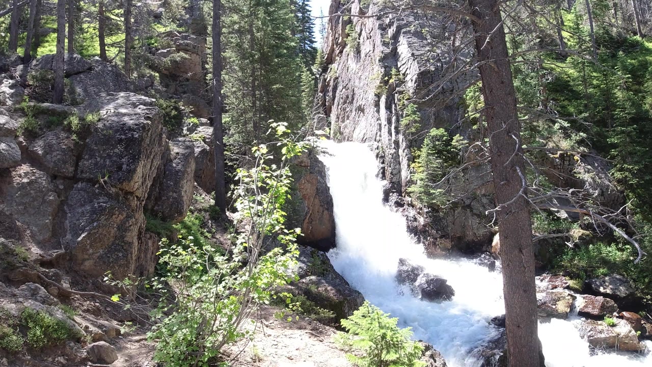 Sunlit mountain waterfall flowing through rocks.