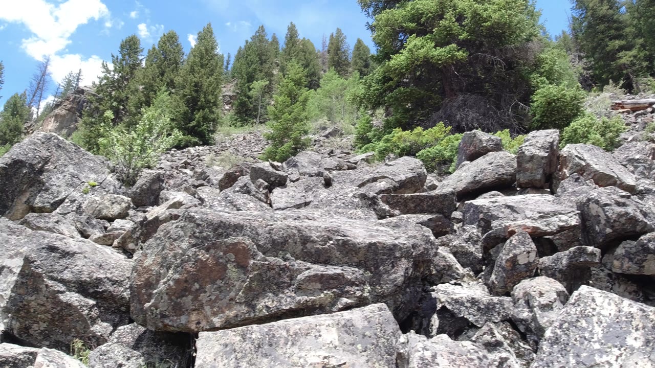 Winter Park, Colorado view of clustered boulders and rough stone ground leading up to dense green trees, with no visible people in the frame.