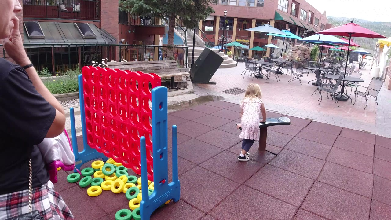 Young girl near red and blue playground equipment on rubber tiles.