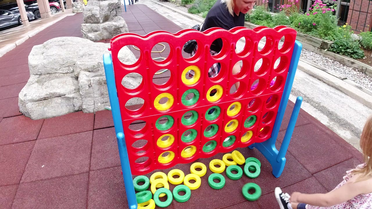 Large red outdoor ring game with a young girl partly visible at the edge.