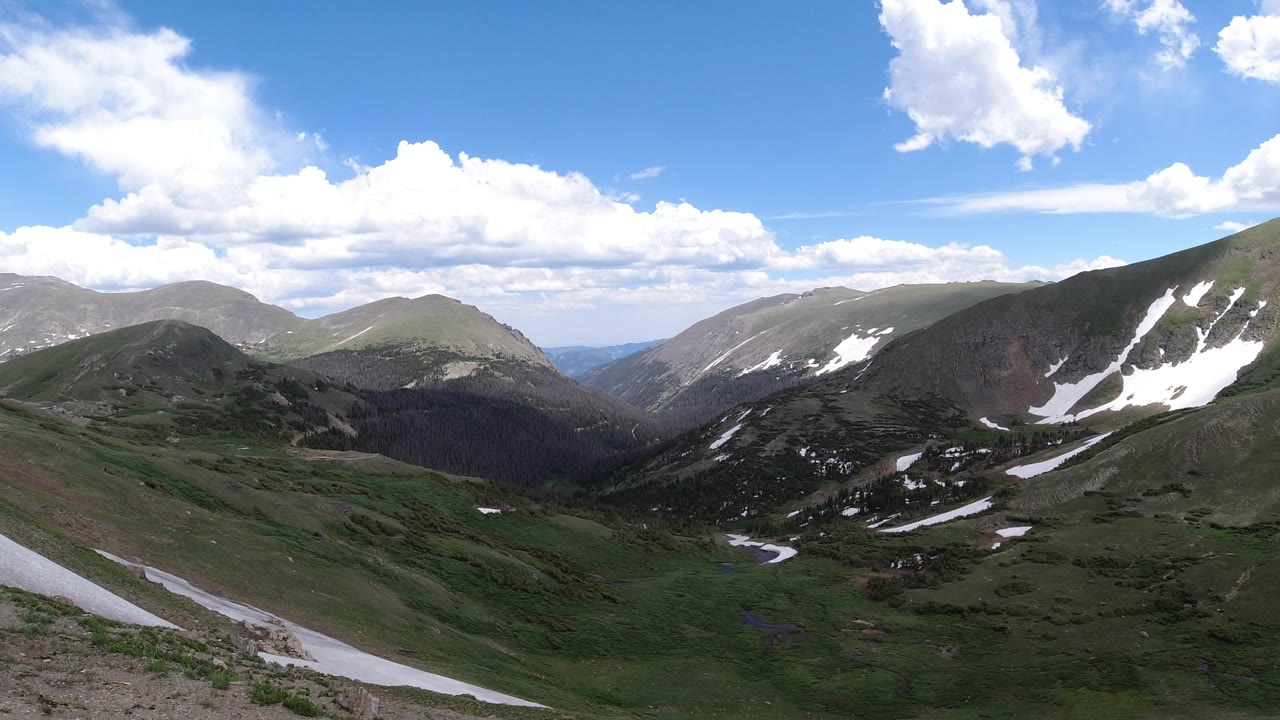 Snow-streaked mountain slope above green valley