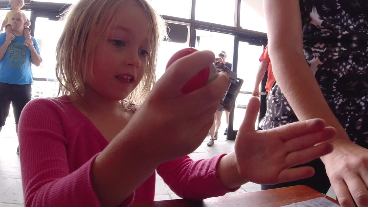 Young girl in a pink top holds a small action camera near an adult woman.