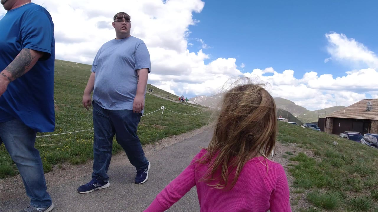 Girl in pink walking behind adults on a mountain path.