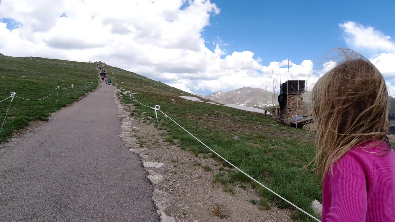 Girl in a pink top beside an uphill paved mountain path.