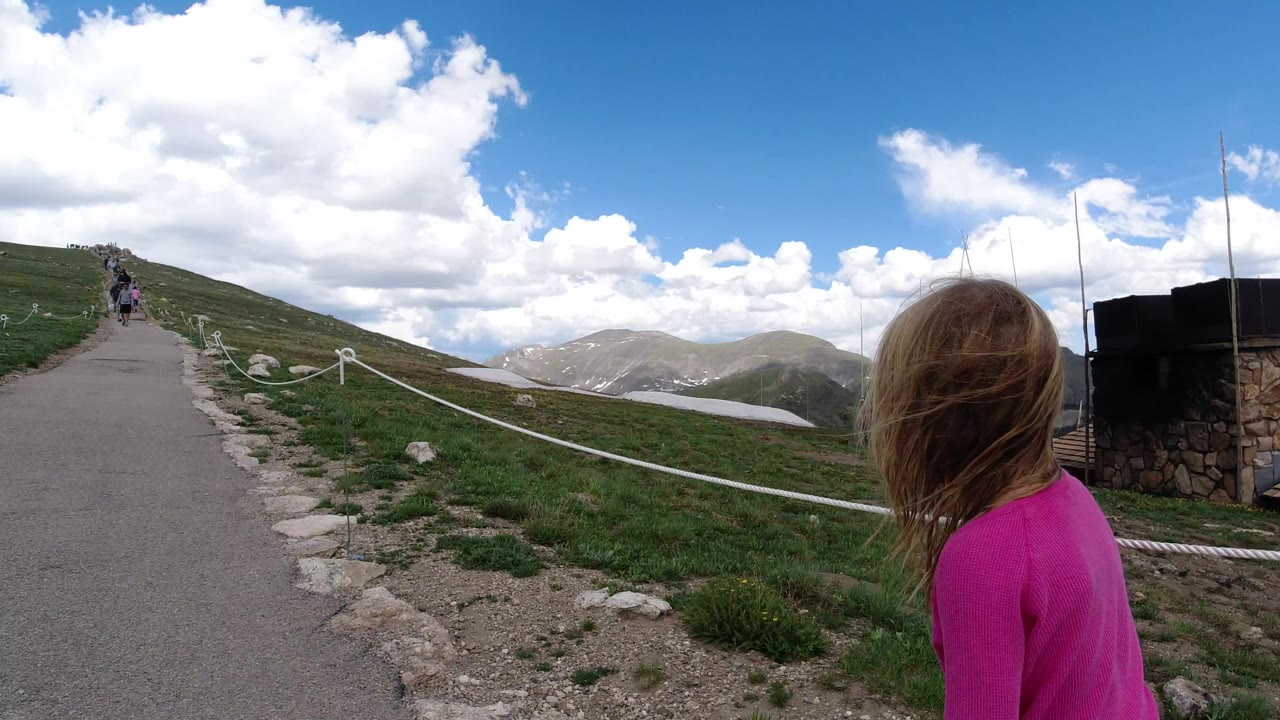 Rope-lined mountain path with a person in pink seen from behind