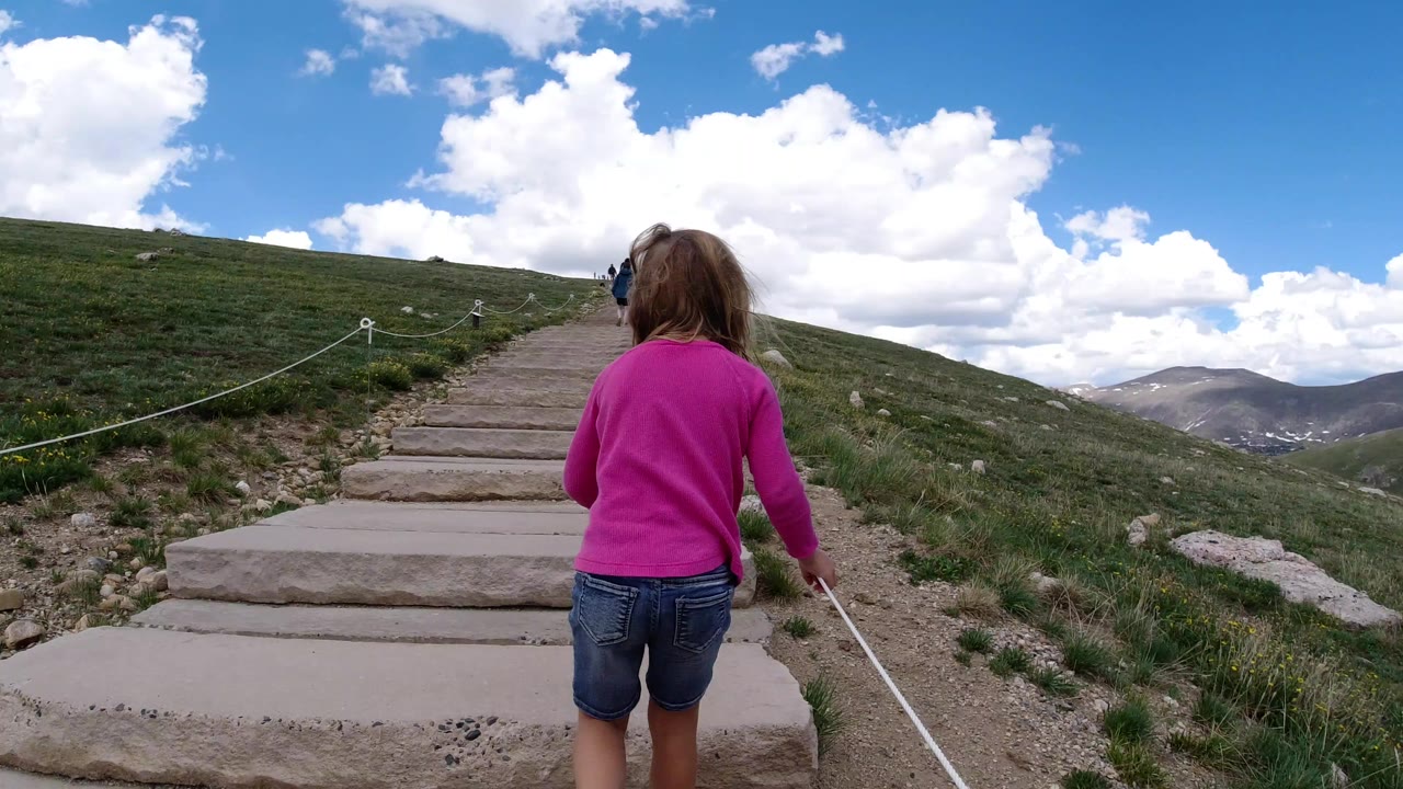Young girl walking up stone steps on a mountain trail.