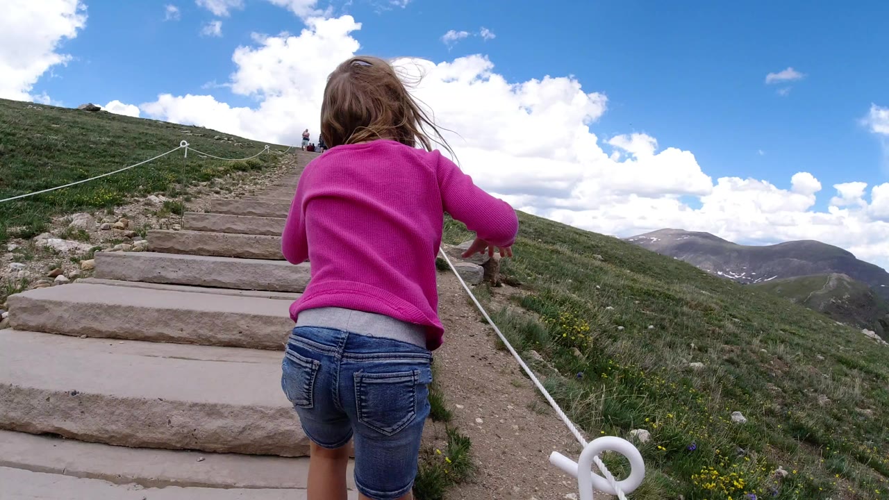 Young girl in a pink top walking up stone mountain steps.