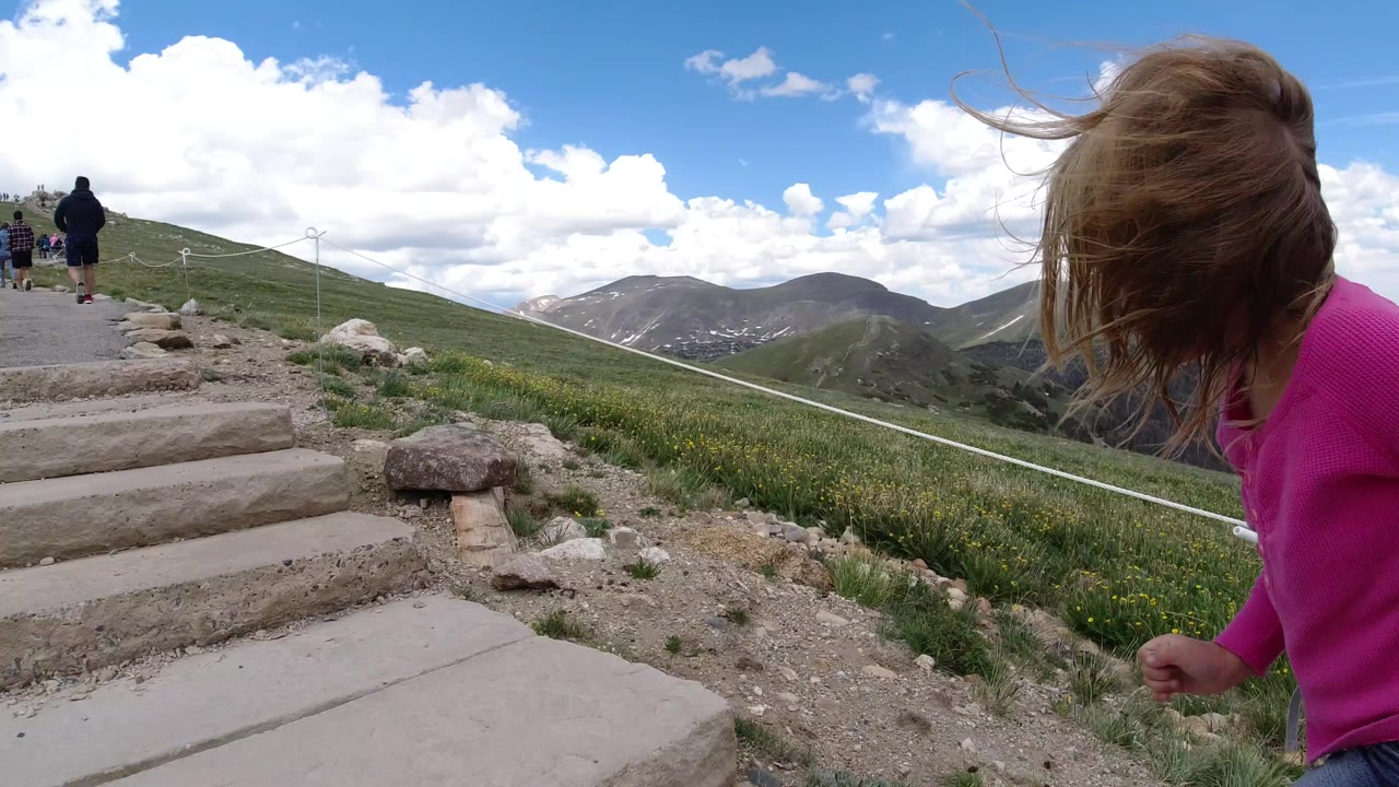 Child in pink beside mountain steps with hikers ahead