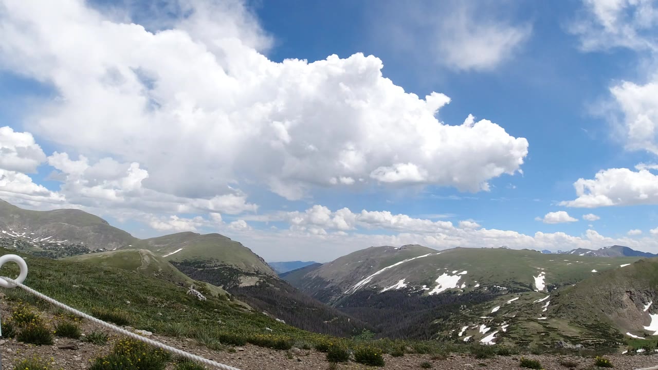 Wide mountain ridges beneath large white clouds and blue sky.