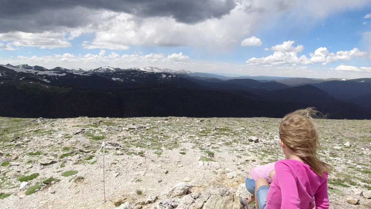 Young girl seen from behind on a rocky mountain overlook.
