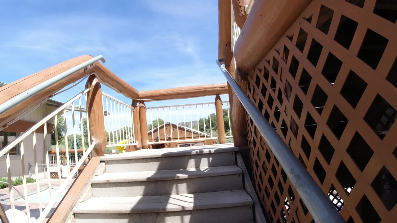 Outdoor wooden stairs in Winter Park, Colorado with gray treads, white railings, wood posts, lattice paneling, blue sky, and no visible people in this opening frame.