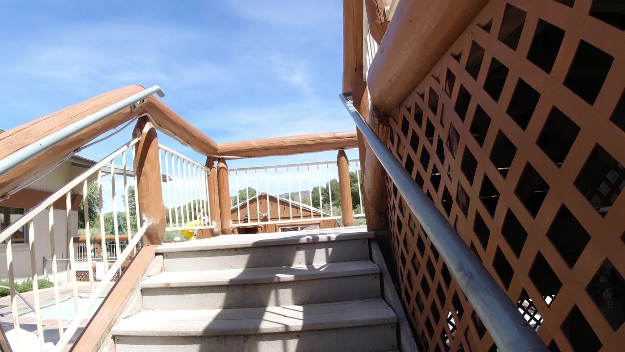 The stairway remains centered in Winter Park, Colorado, with the wood lattice panel filling the right side and white railing posts leading toward nearby buildings, with no visible people.
