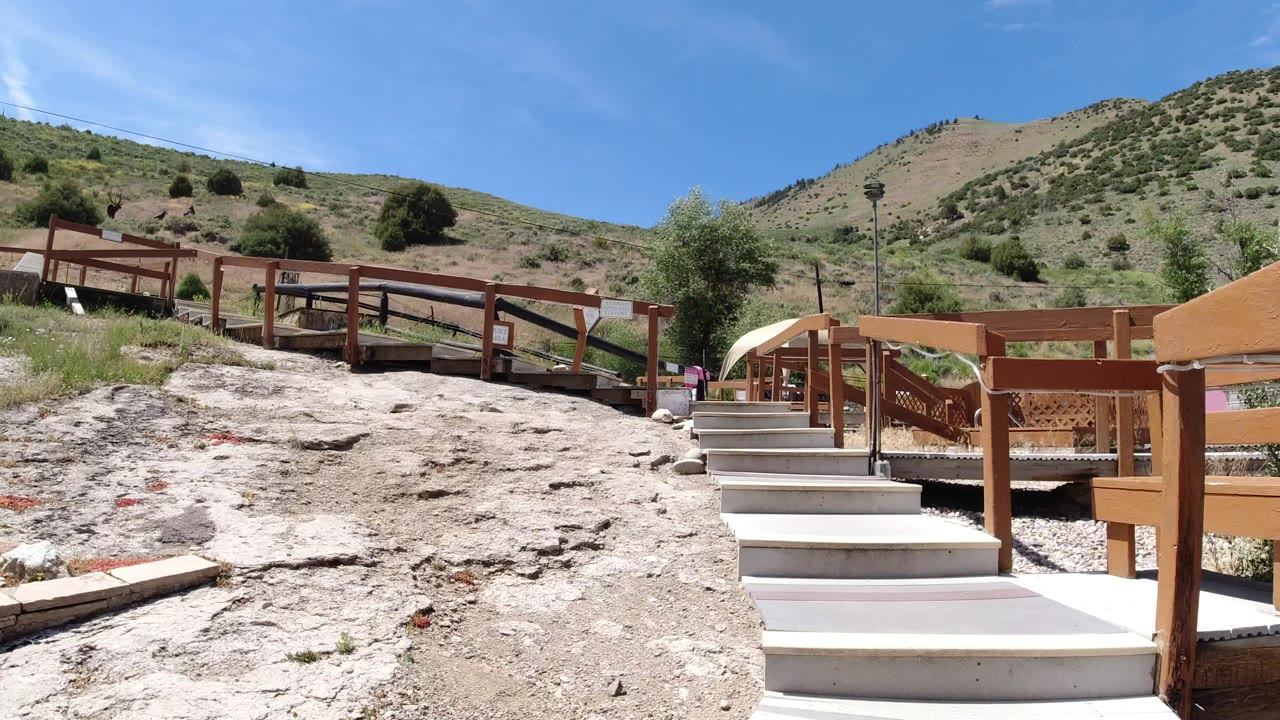 A low view in Winter Park, Colorado frames pale stone steps in front, wood fencing across the middle, scrubby hillside behind, and no visible people.