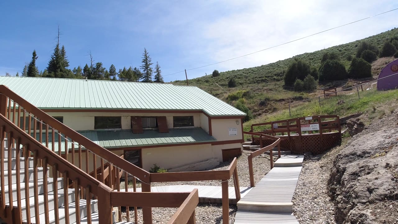 Green-roofed building, wooden walkway, rocky ground, hillside, and purple structure.
