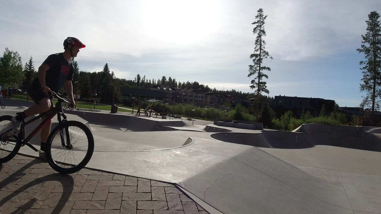 Helmeted cyclist at the edge of a concrete skatepark.