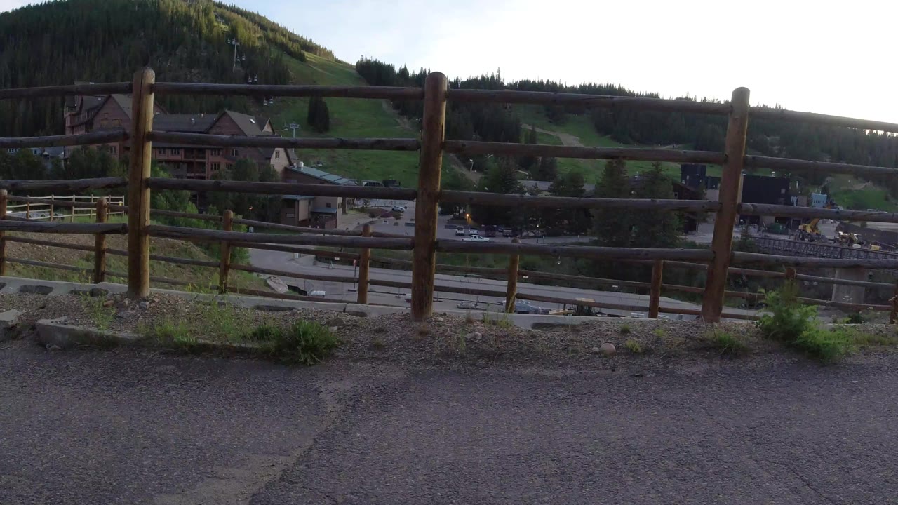 Wooden fence above a mountain road and village buildings