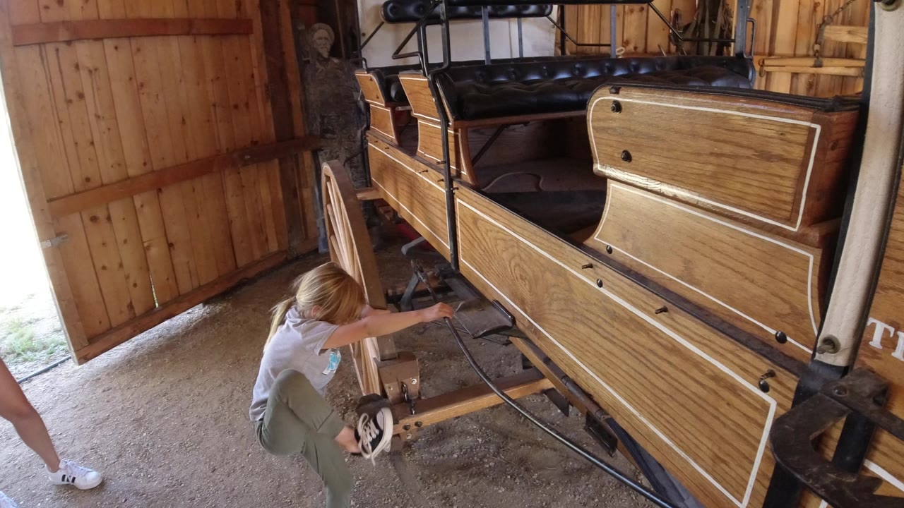 Child crouching beside a wooden wagon display.