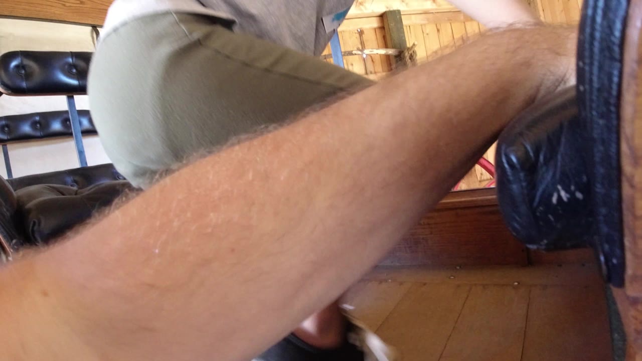 Close view of a person's leg and arm beside black padded bench seating.