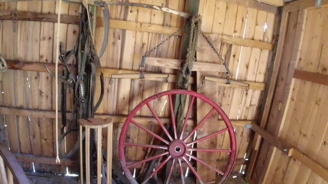 Red spoked wheel leaning inside a wooden shed