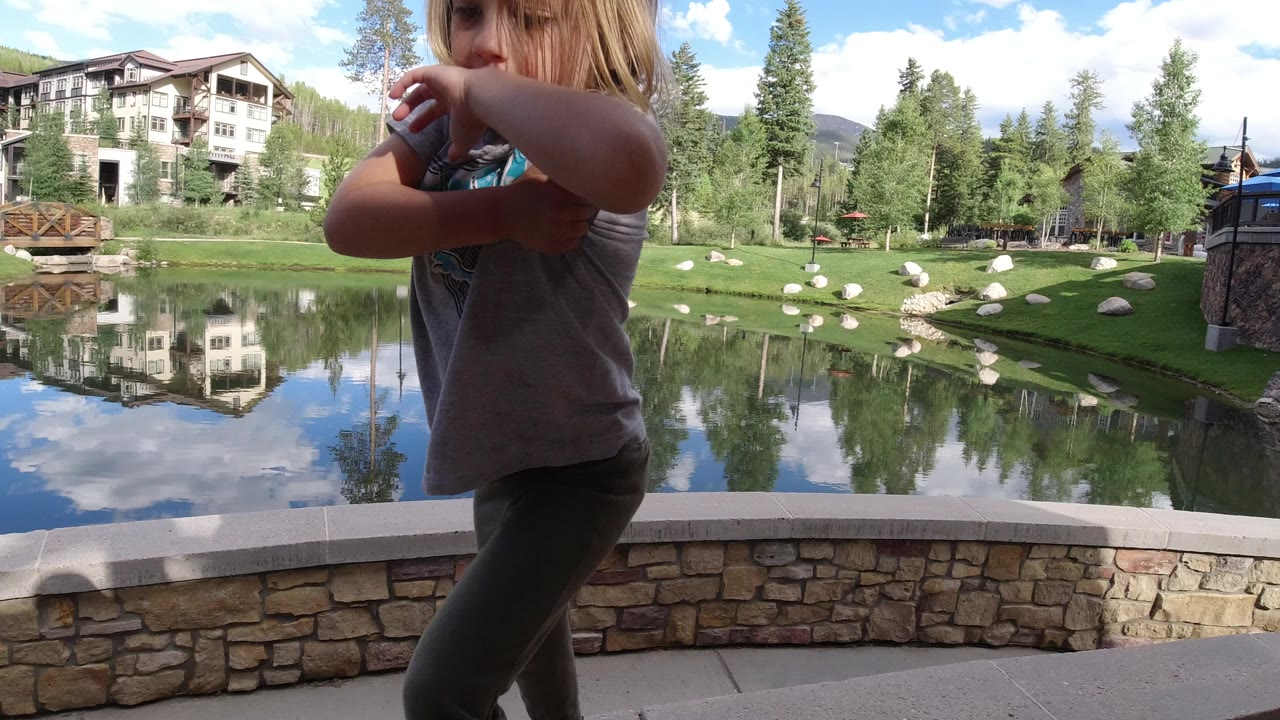 Young girl partly in frame beside a reflective lake and lodge buildings.