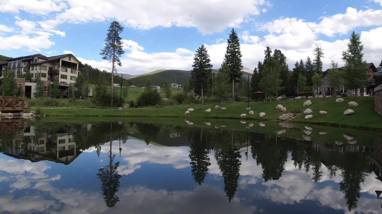 Wide lake view with trees, homes, rocks, and cloud reflections