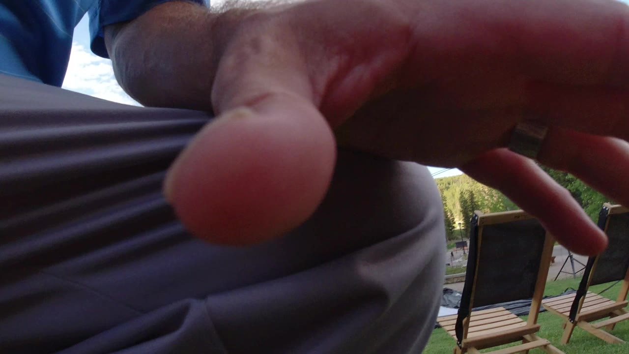 At 0:00 in Winter Park, Colorado, a close hand and gray pants obscure most of the frame while deck chairs and outdoor lift-area details sit behind them.