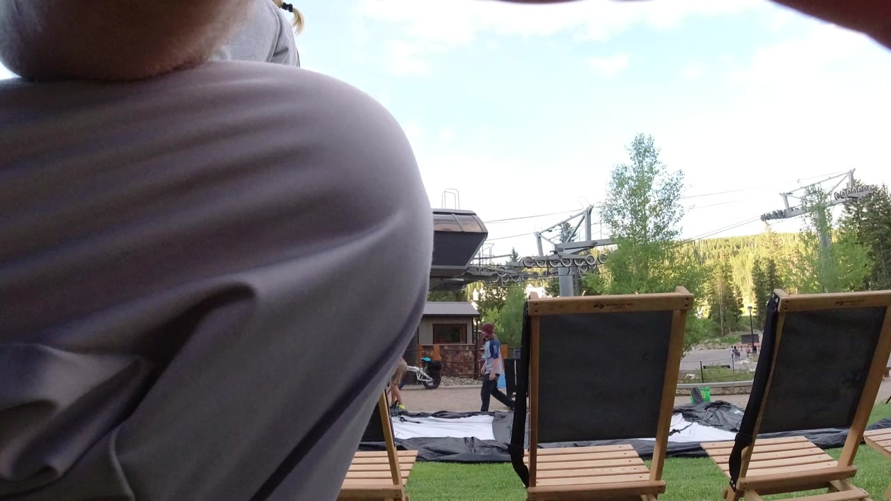 Low view of lawn chairs and grass partly blocked by a person's leg.