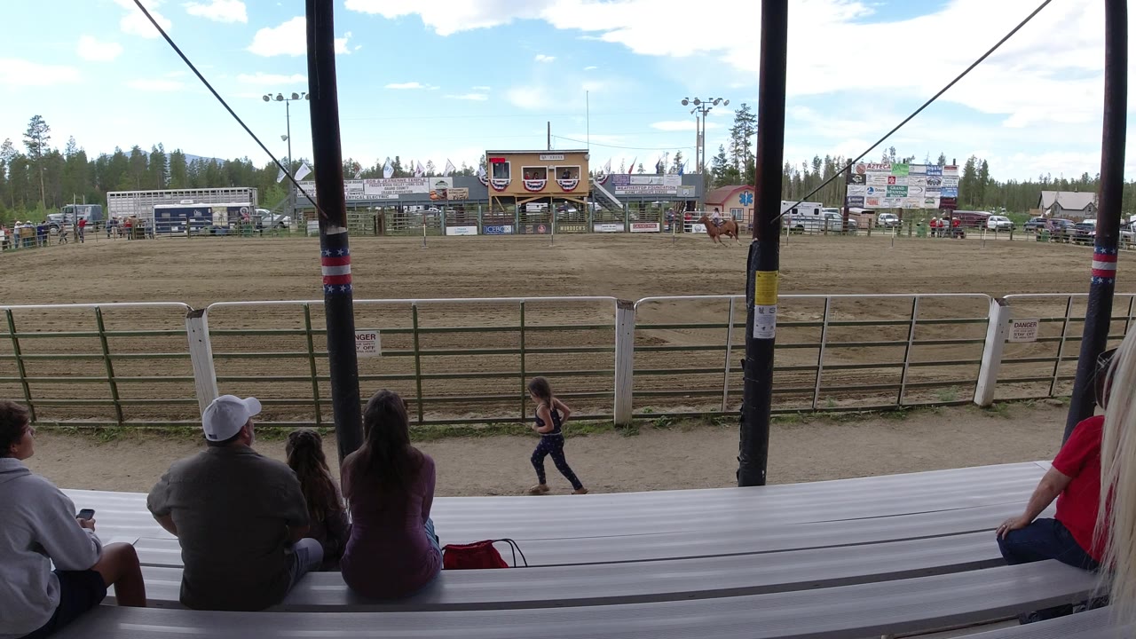 Horse track scene viewed from covered bleachers with a rider in the arena.
