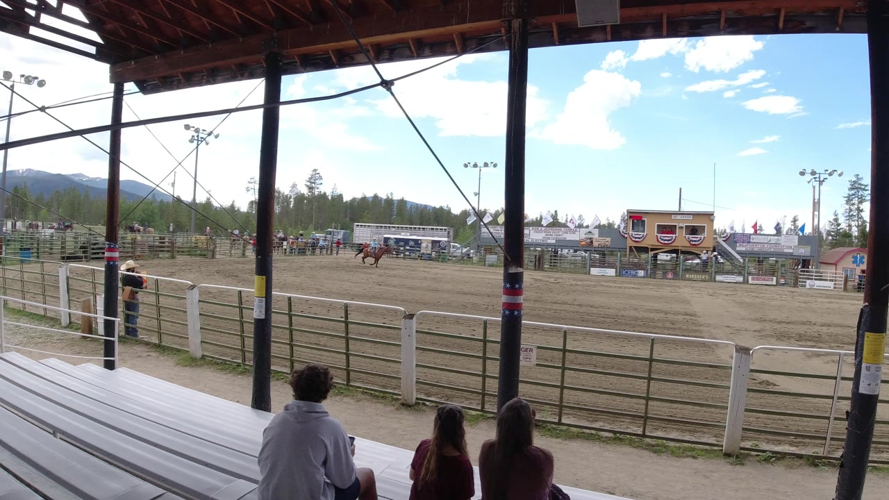 The horse and rider are farther across the Winter Park arena while a few spectators sit on the metal bleachers beneath dark roof beams.