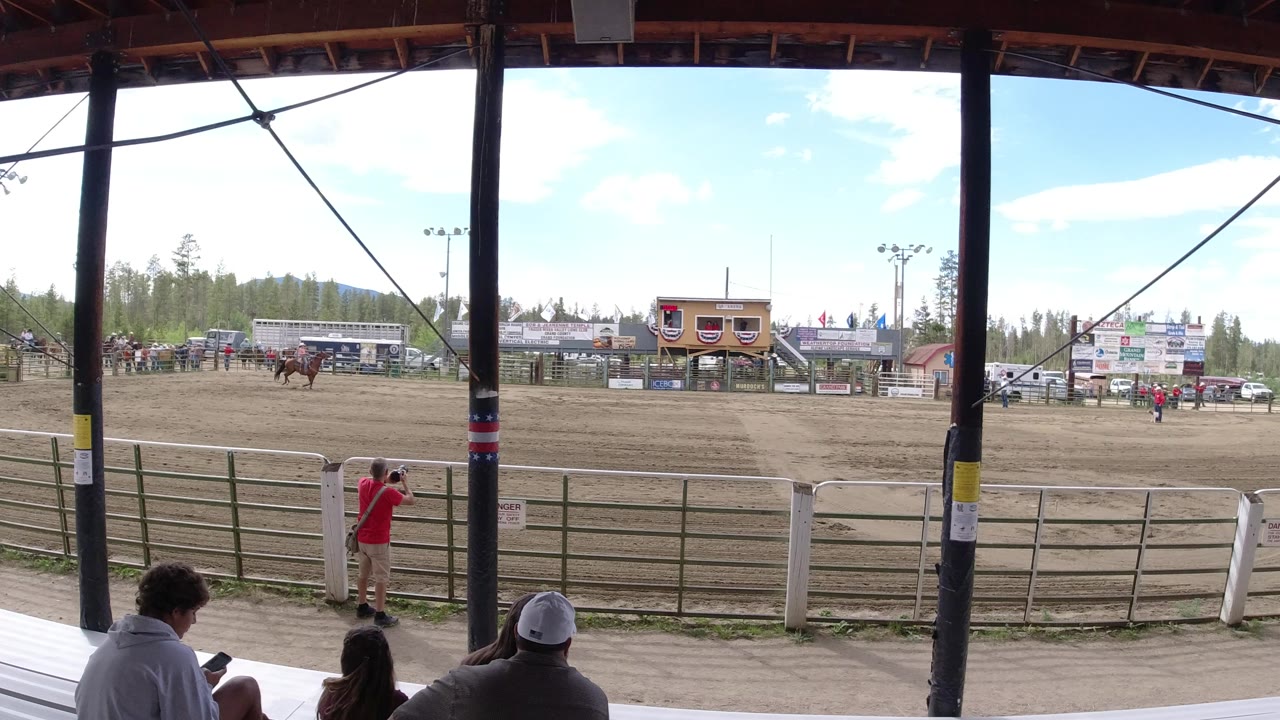 Wide rodeo arena seen from shaded grandstand seating.