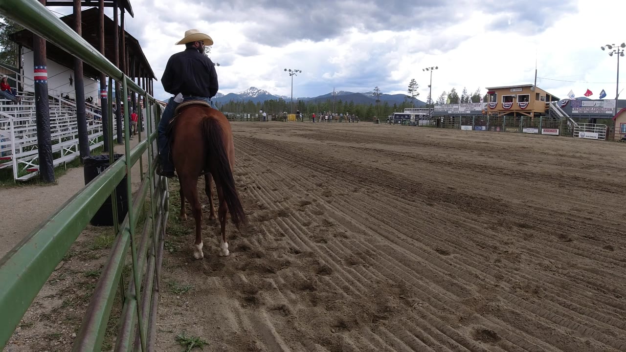 At 0:01 in Winter Park, Colorado, the horse remains near the left rail while the open raked track, white fencing, and cloudy mountain backdrop fill the view.