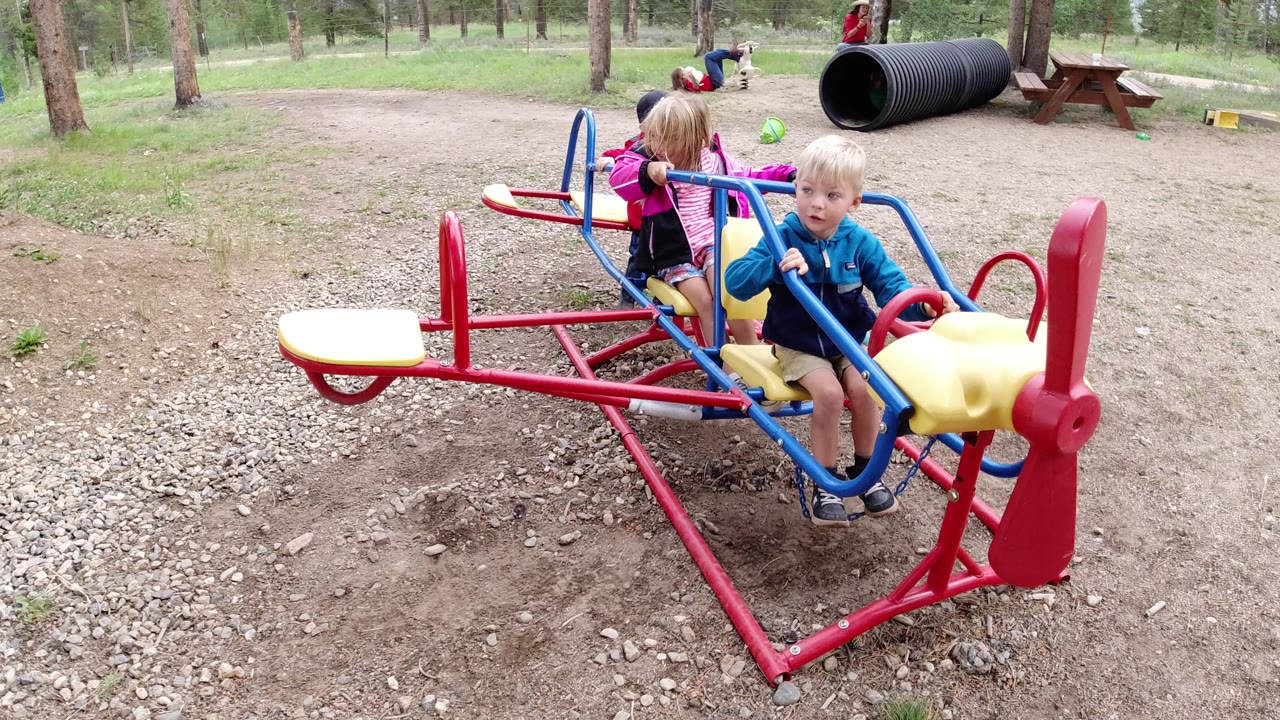 Children continue playing on the colorful airplane seesaw.