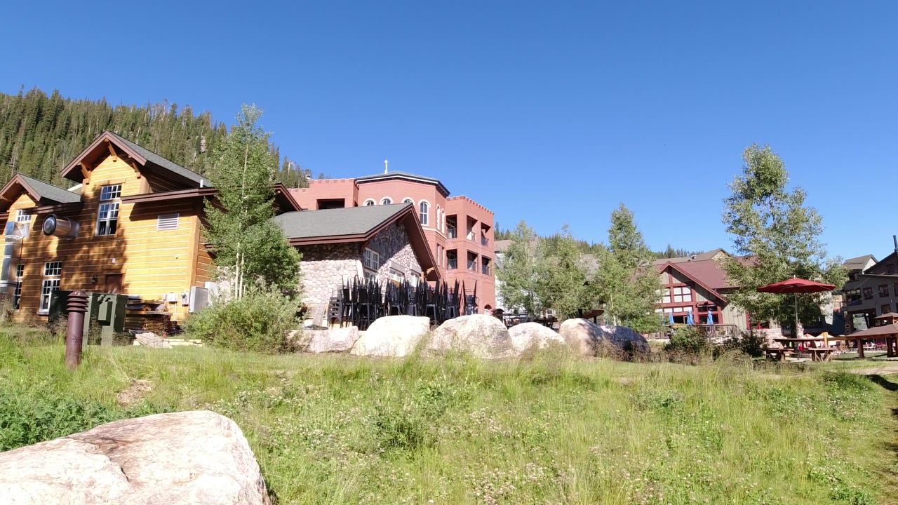 Wide frame of Winter Park residential grounds with grass in the foreground, boulders and outdoor seating in the middle, and multiple homes behind them.