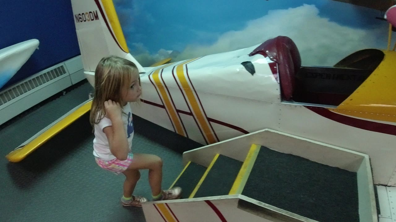In Wheat Ridge, Colorado, the young girl remains near the steps while the white play-plane body and tail fill the frame behind her.