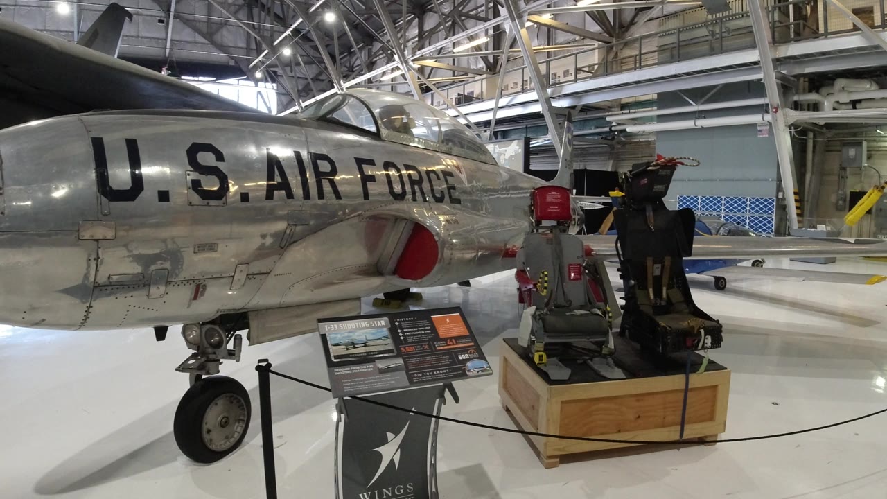 Silver U.S. Air Force aircraft nose beside museum exhibit signs.