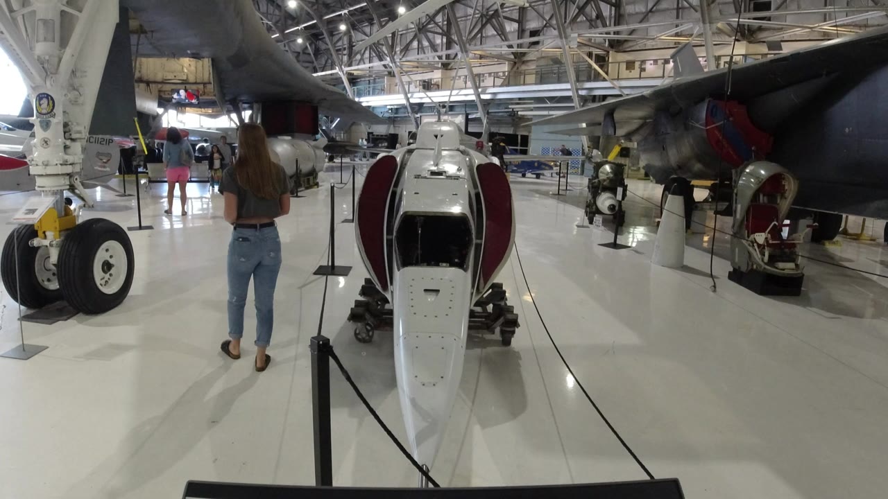 Aircraft hangar display with landing gear, cockpit pod, and a visitor walking away.
